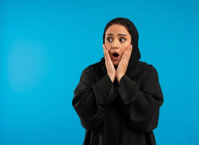 Surprised Arab Woman in Black Abaya on Blue Background