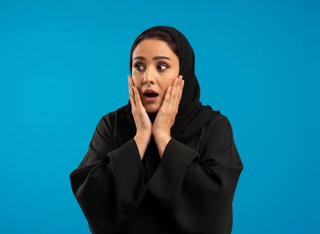 امرأة سعودية مصدومة بالعباءة السوداء بخلفية زرقاء امرأة سعودية مصدومة بالعباءة السوداء بخلفية زرقاء