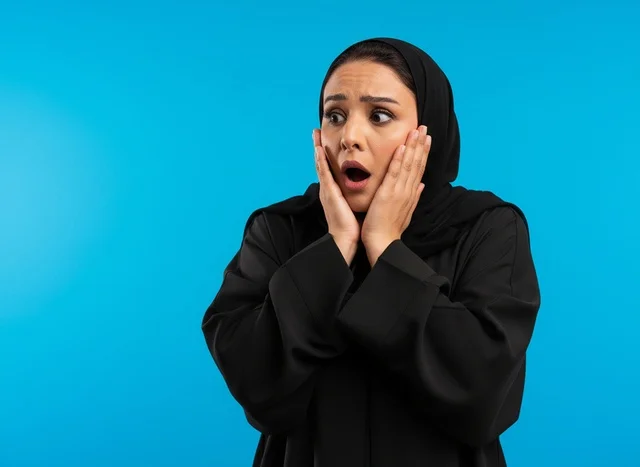امرأة سعودية بالعباءة بتعبيرات وجه مصدومة خلفية زرقاء