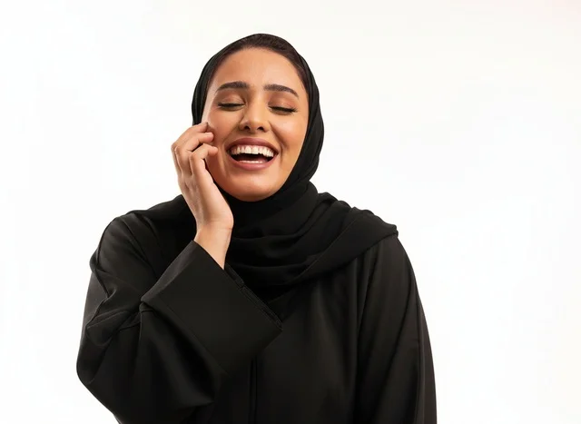 امرأة سعودية بالعباءة السوداء تضحك في استوديو