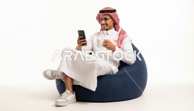 رجل سعودي يجلس على مقعد استرخاء مع هاتف ذكي