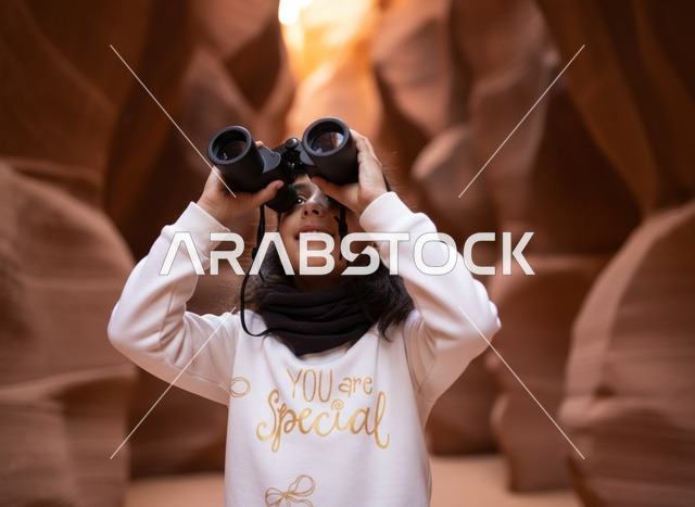 Arab Girl Using Binoculars in Orange Desert Canyon