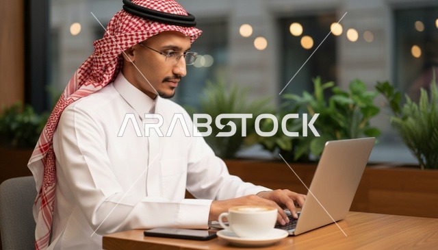رجل سعودي يعمل على الكمبيوتر المحمول في مقهى