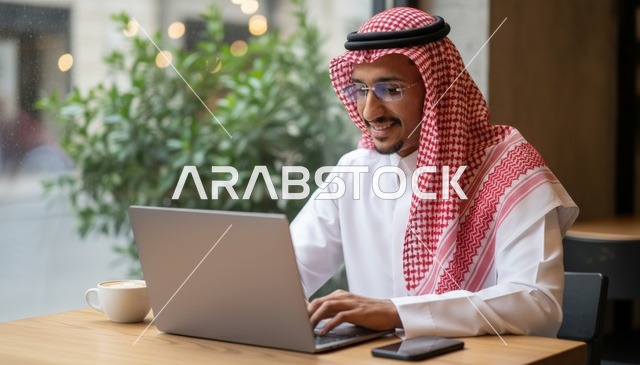 رجل سعودي يعمل على الكمبيوتر المحمول في مقهى