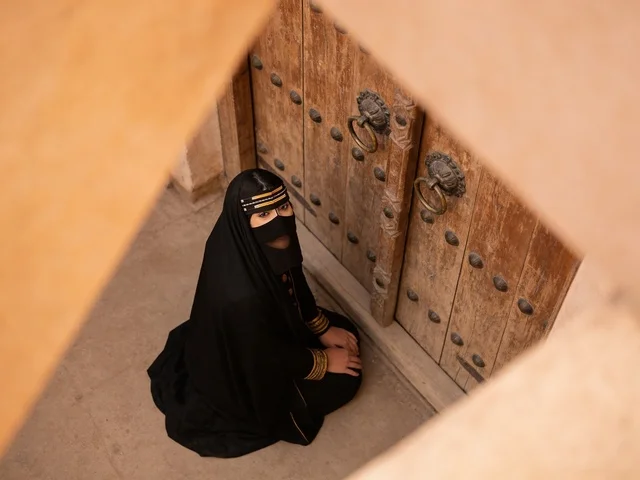امرأة سعودية بالزي التقليدي أمام باب تراثي