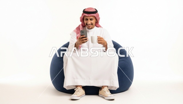 رجل سعودي مع هاتف ذكي وكوب على كرسي بين باج
