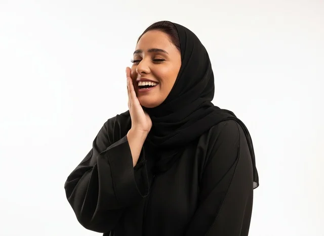 امرأة سعودية تضحك بالعباءة السوداء في الاستوديو