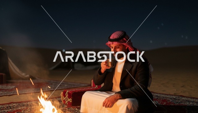 رجل سعودي بجانب شبة نار في الصحراء ليلاً