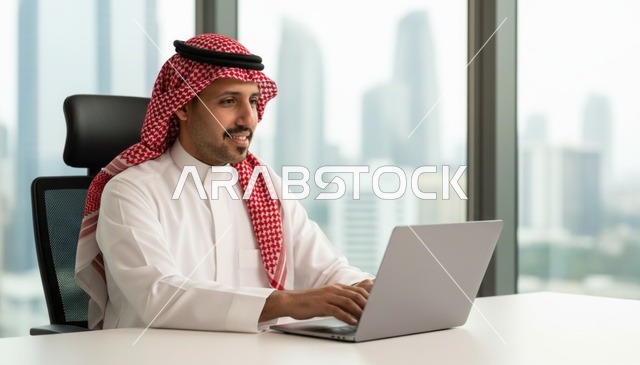 رجل سعودي يعمل على الكمبيوتر في مكتب حديث