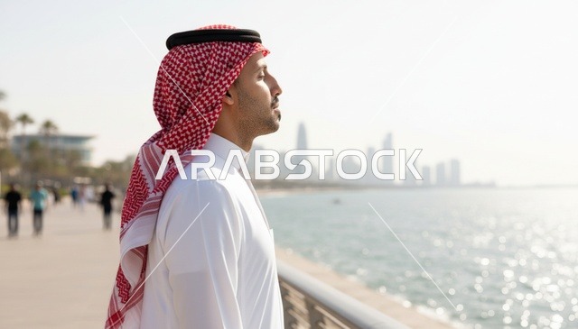 رجل سعودي بالثوب والشماغ على الممشى الساحلي