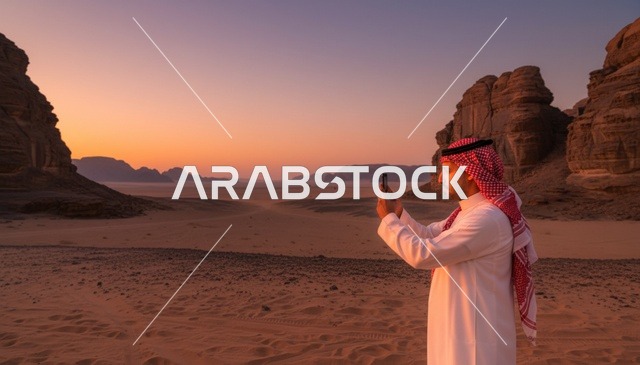رجل سعودي يصور في الصحراء وقت الغروب
