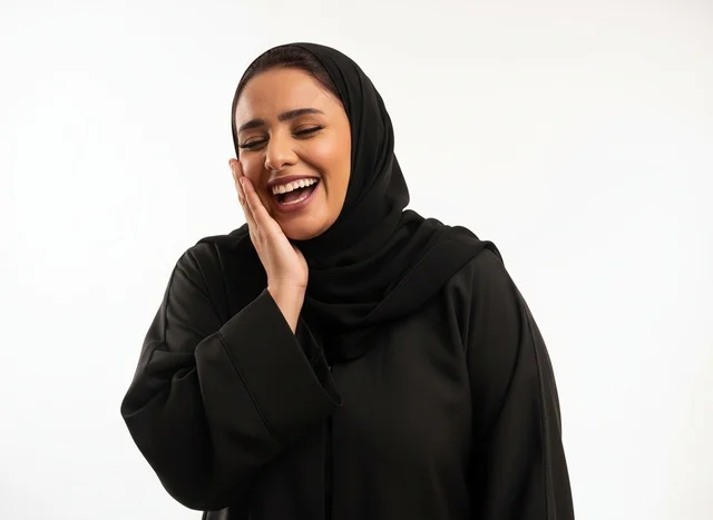 امرأة سعودية بالعباءة السوداء تضحك بخلفية بيضاء