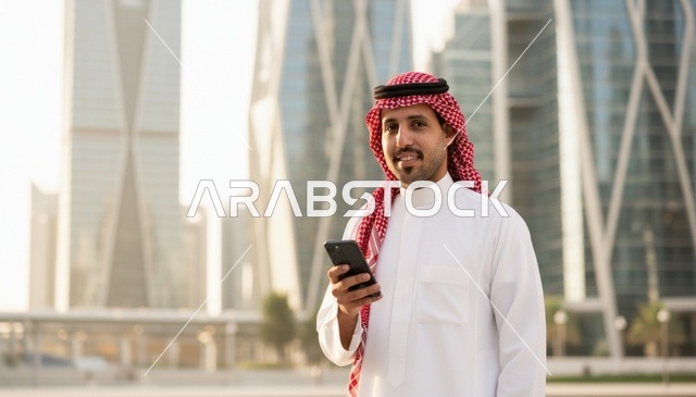 رجل سعودي مع هاتف ذكي في المركز المالي بالرياض