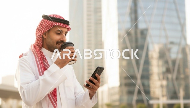 رجل سعودي بالثوب مع قهوة وهاتف ذكي