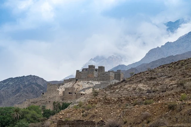 حصن حجري تقليدي على جبل سعودي مع الغيوم