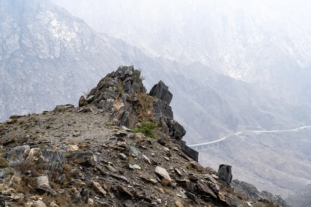 Rugged Mountain Peaks with Misty Valley Bridge View