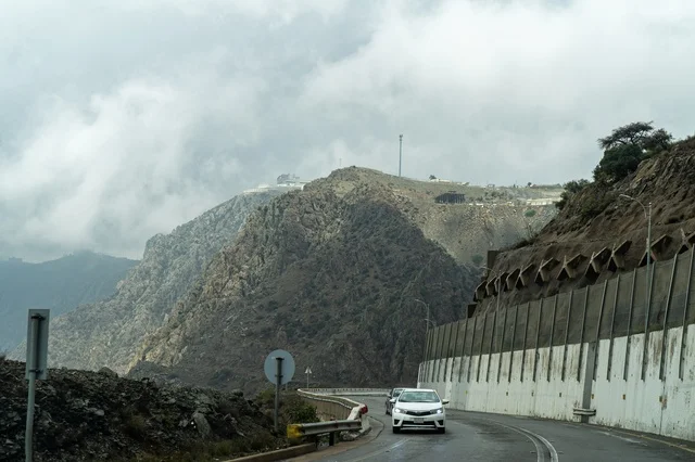 سيارات على طريق جبلي ضبابي في المرتفعات الصخرية العالية