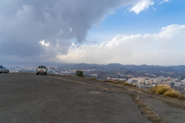 White Pickup Truck Overlooking City with Stormy Sky