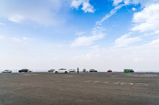Cars Parked in Open Asphalt Lot Under Blue Sky