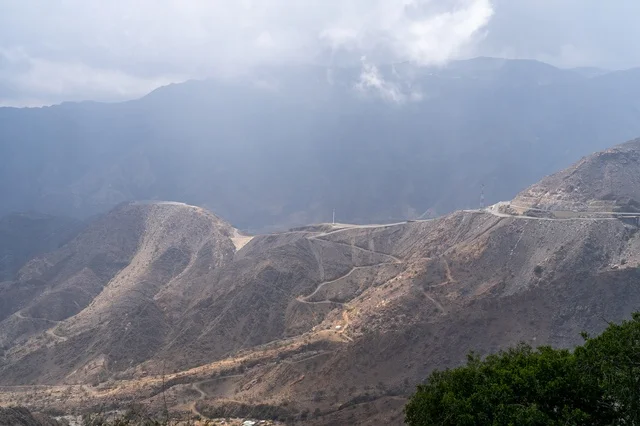 منظر الجبال الوعرة تحت الضباب مع طريق ترابي متعرج