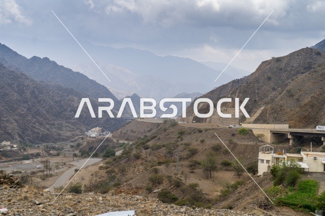 طريق جبلي عبر وادٍ صخري تحت سماء غائمة