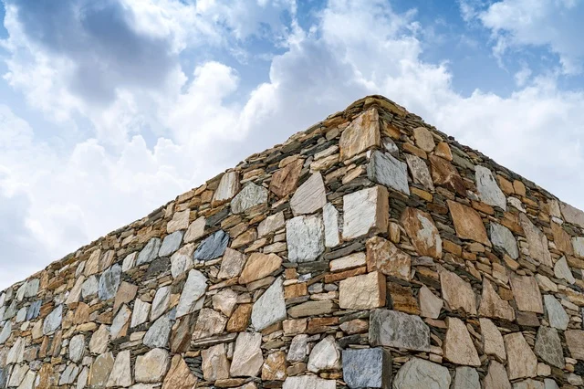 Traditional Stone Wall Building Corner Under Cloudy Sky