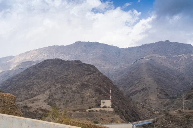 تضاريس جبال صخرية مع برج اتصالات ومبنى تحت الغيوم تضاريس جبال صخرية مع برج اتصالات ومبنى تحت الغيوم
