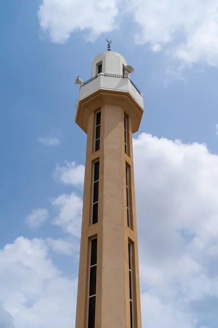 مئذنة مسجد حديثة مع مكبرات صوت تحت السماء الزرقاء