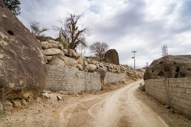 Dirt Road Between Large Boulders and Concrete Walls