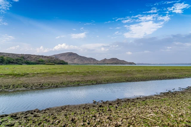 Water Canal in Green Field with Mountains Landscape