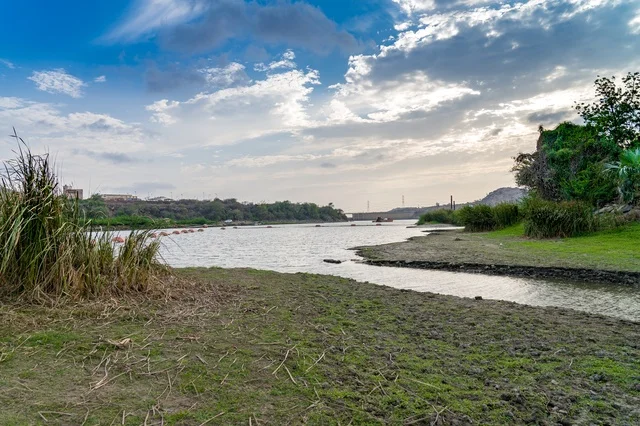 Wide River Landscape with Grassy Banks and Cloudy Sky