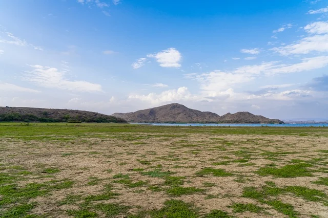 Wide Mountain Landscape and Grassy Field under Blue Sky