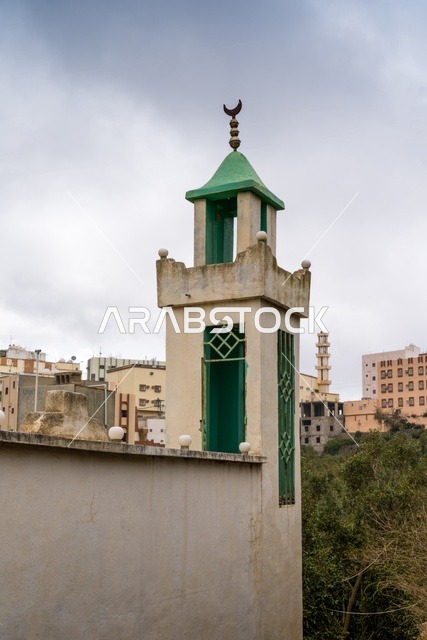 مئذنة مسجد بسقف أخضر وهلال تحت سماء غائمة