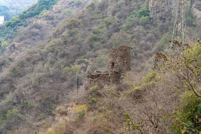 Ancient Stone Tower on Mountain with Power Lines