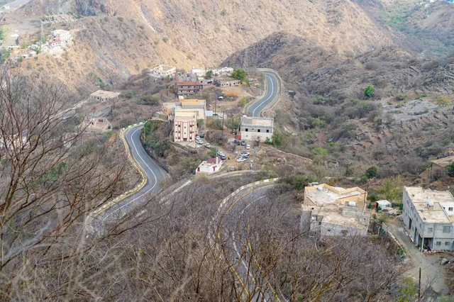 طريق جبلي متعرج ومنظر جوي للقرية