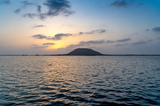 ظل الجبل فوق مياه هادئة عند الغروب