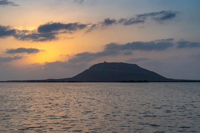 صورة ظلية للجبل فوق البحر الهادئ في وقت الغروب