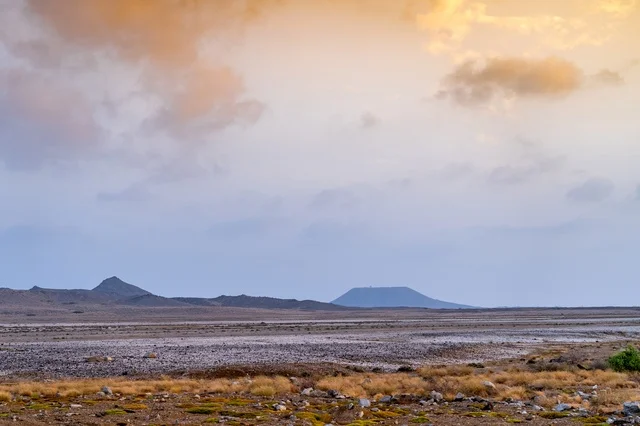 منظر طبيعي صحراوي مع جبال بركانية وقت الغروب