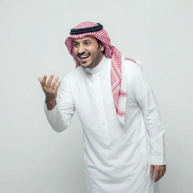 شاب سعودي بالثوب التقليدي يضحك أمام خلفية استوديو بيضاء