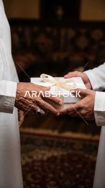 تبادل صندوق هدية أبيض بين رجال بالزي السعودي التقليدي