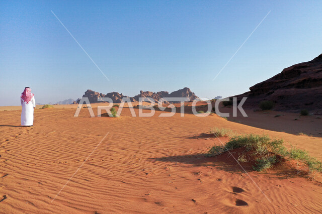 صورة للتكوينات الصخرية الجذابة في منطقة تبوك ، رجل عربي خليجي سعودي في صحراء بجدة نيوم في شمال غرب السعودية ، مناظر طبيعية للرمال الذهبية ، جبال ذات تشكيلات صخرية  ، معالم حضارية سياحية في المملكة العربية السعودية .