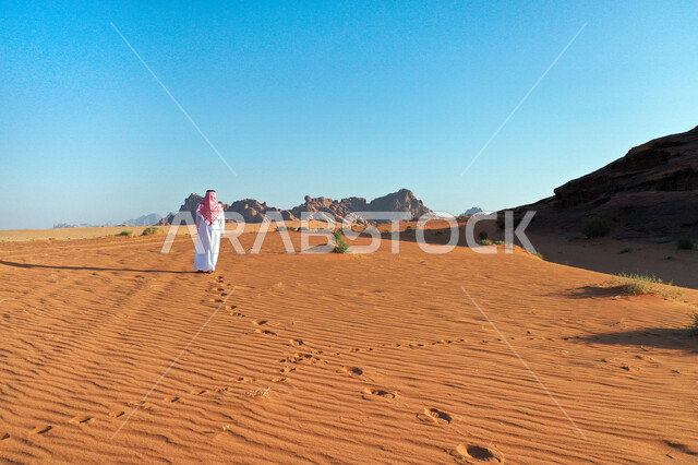 صورة للتكوينات الصخرية الجذابة في منطقة تبوك ، رجل عربي خليجي سعودي في صحراء بجدة نيوم في شمال غرب السعودية ، مناظر طبيعية للرمال الذهبية ، جبال ذات تشكيلات صخرية  ، معالم حضارية سياحية في المملكة العربية السعودية .