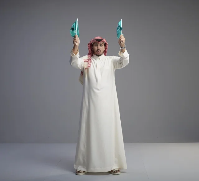 رجل سعودي يحمل الأعلام الوطنية في الاستوديو