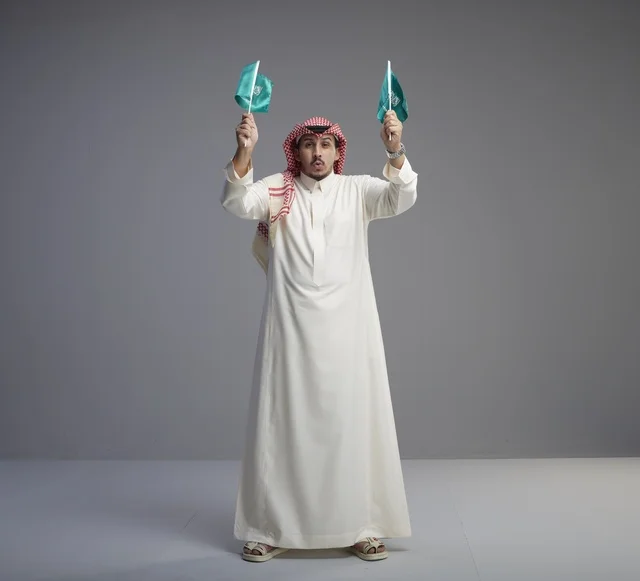 رجل سعودي يحمل العلم السعودي في الاستوديو