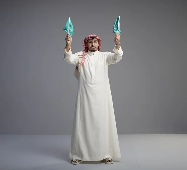 Saudi Man Holding Flags in Traditional Dress Studio Shot