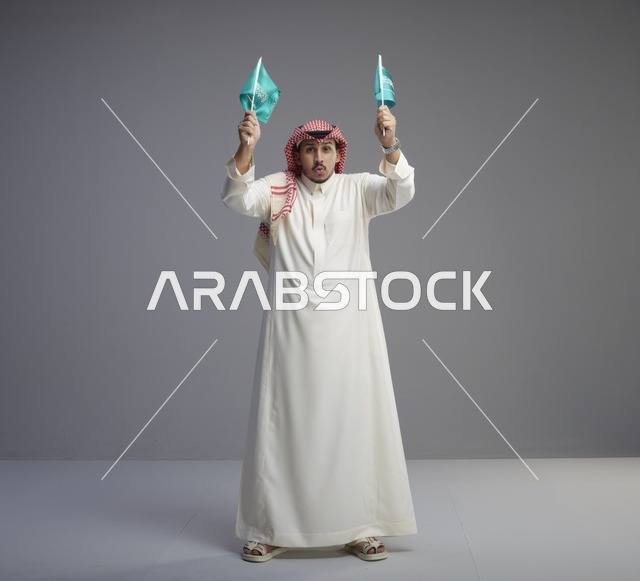 رجل سعودي يحمل الأعلام الوطنية في الاستوديو