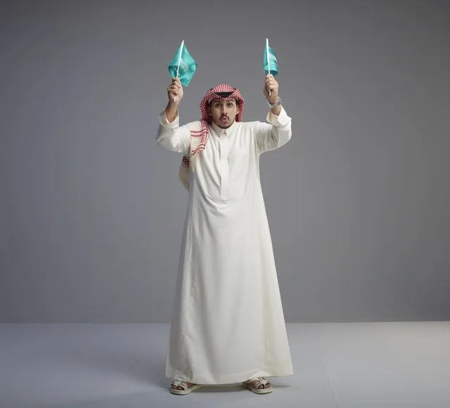 رجل سعودي يحمل الأعلام الوطنية في الاستوديو