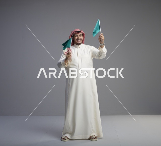 رجل سعودي يحمل أعلام المملكة العربية السعودية بالزي التقليدي