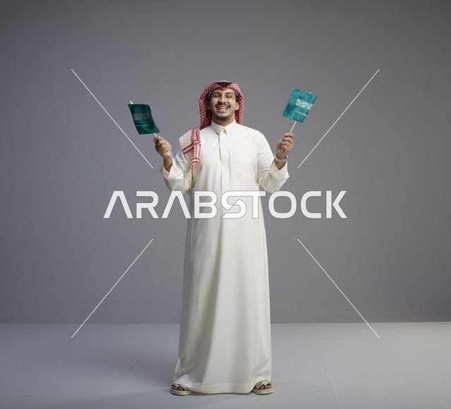 رجل سعودي يحمل الأعلام الوطنية السعودية خلفية رمادية