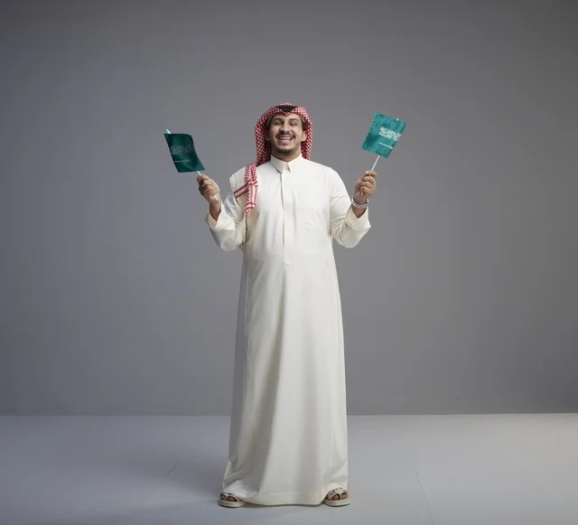 Saudi Man Holding National Flags on Grey Background